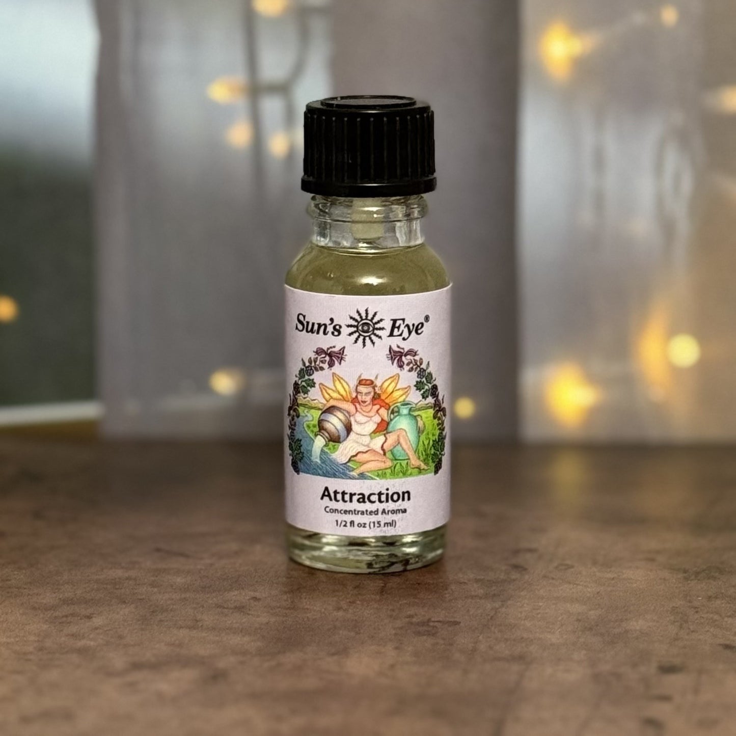 Bottle of Sun's Eye Attraction essential oil with a blurred background