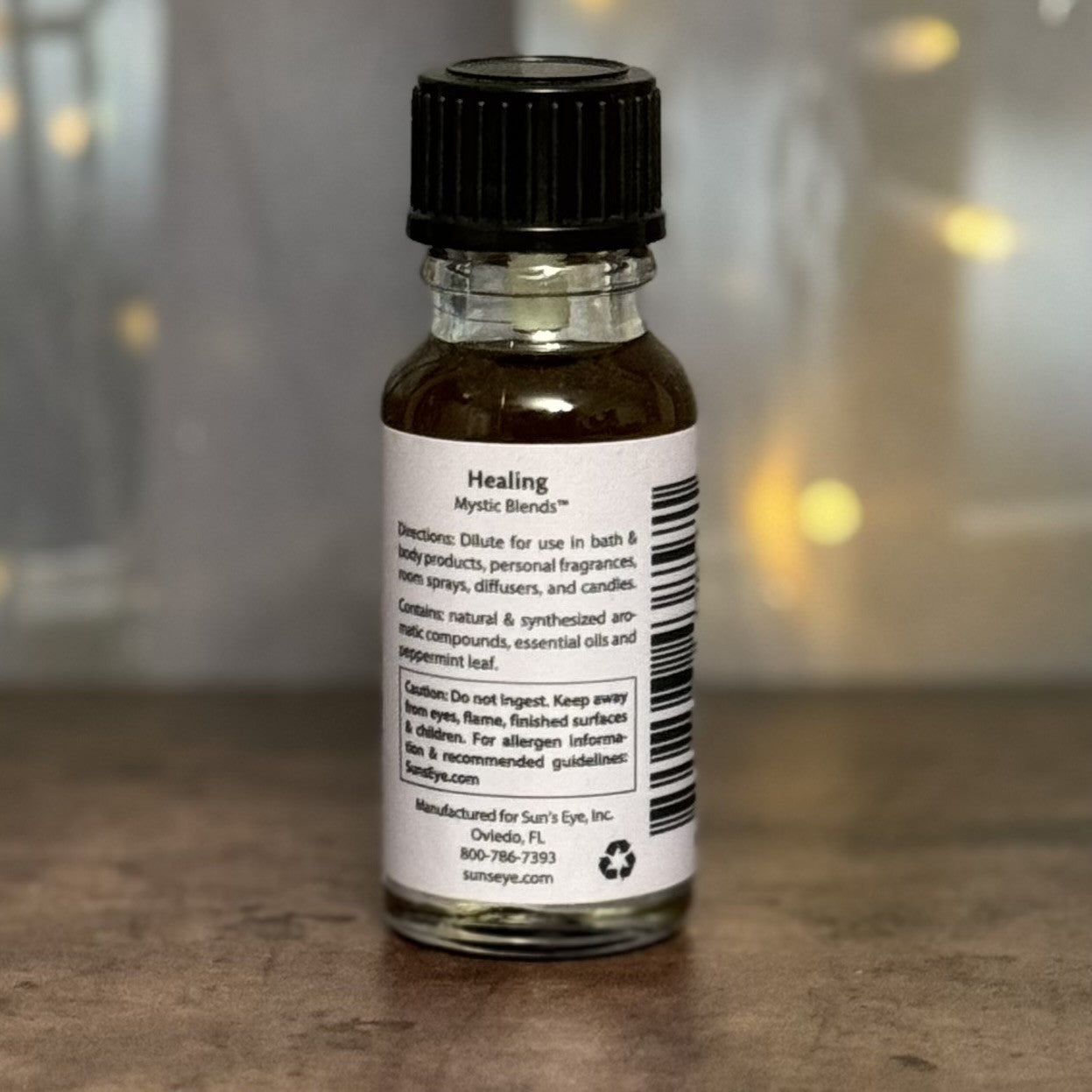 Small glass bottle with a black cap on a wooden surface, featuring a label.
