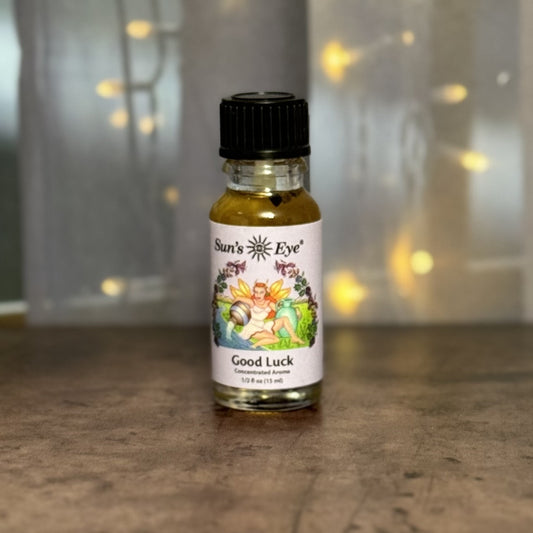 Bottle of 'Good Luck' perfume by Sun's Eye on a wooden surface with a blurred background.