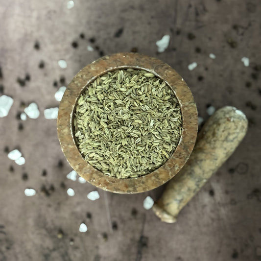 Wooden container filled with fennel on a textured surface