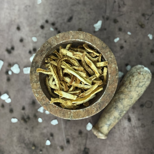 Mortar and pestle with dried  orange peels on a textured surface