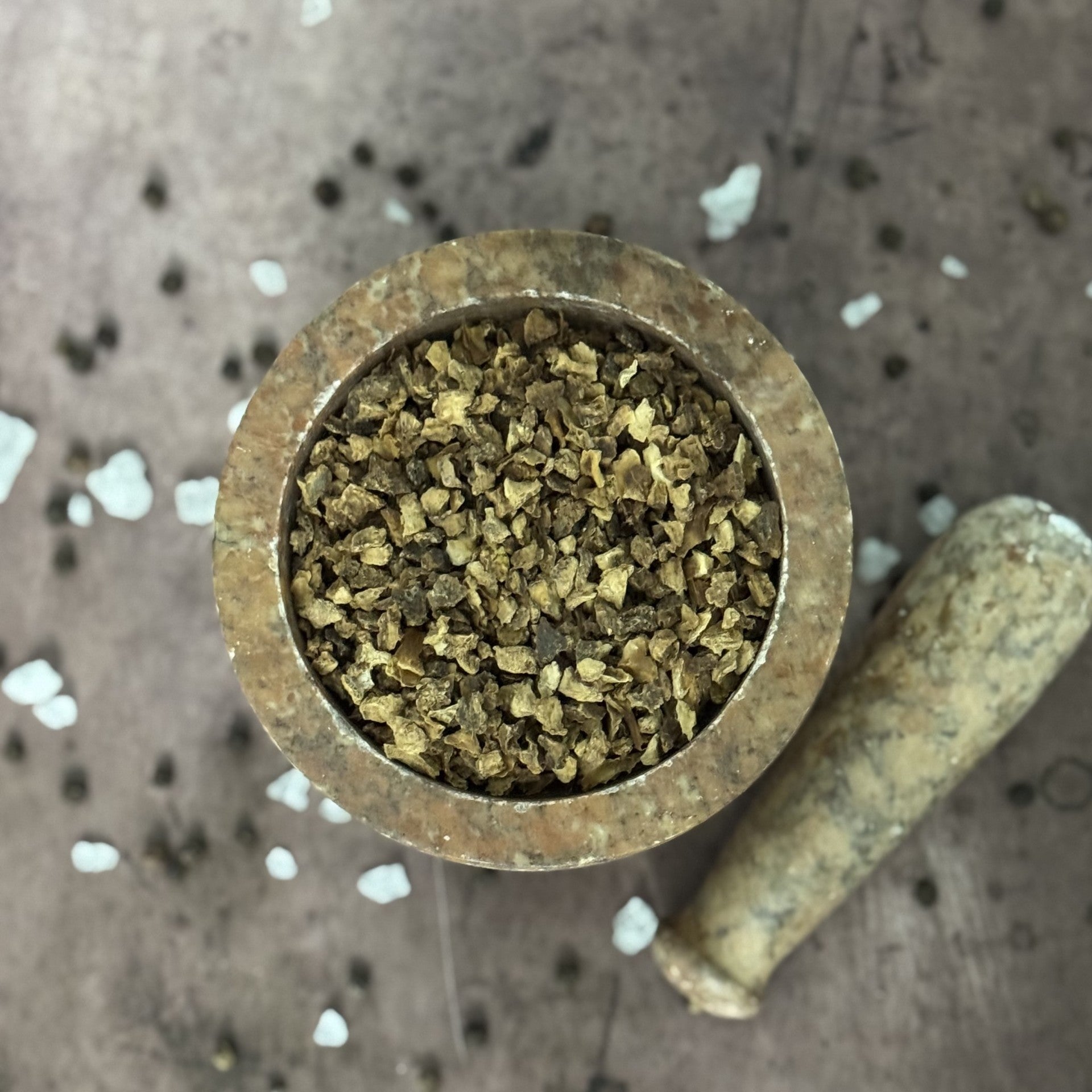 Small brass container filled with a green substance on a textured surface