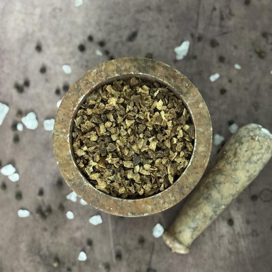 Small brass container filled with a green substance on a textured surface