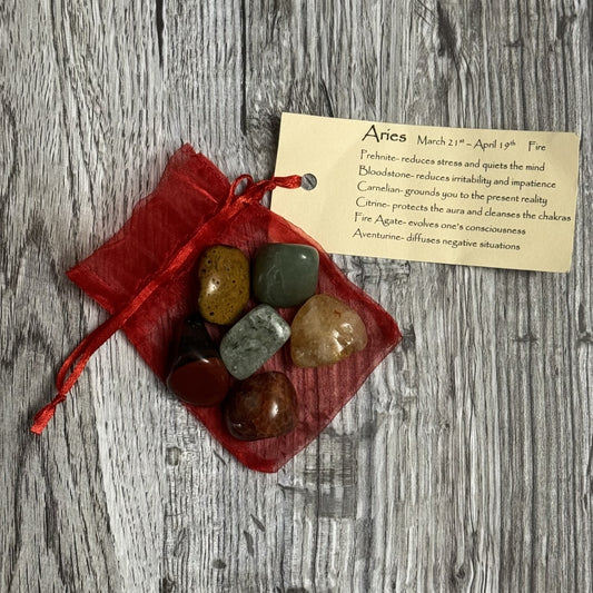 Set of stones in a red bag with an informational card on a wooden surface