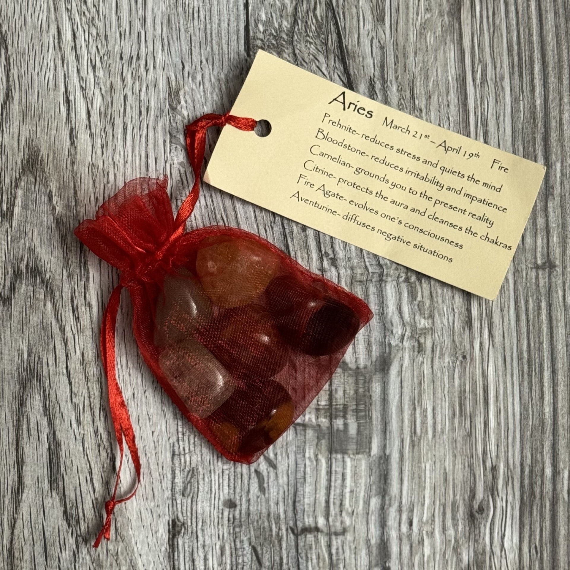 Red drawstring bag with stones and a tag on a wooden surface