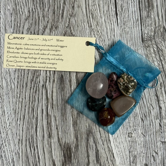 Collection of crystals in a blue drawstring bag with a card on a wooden surface