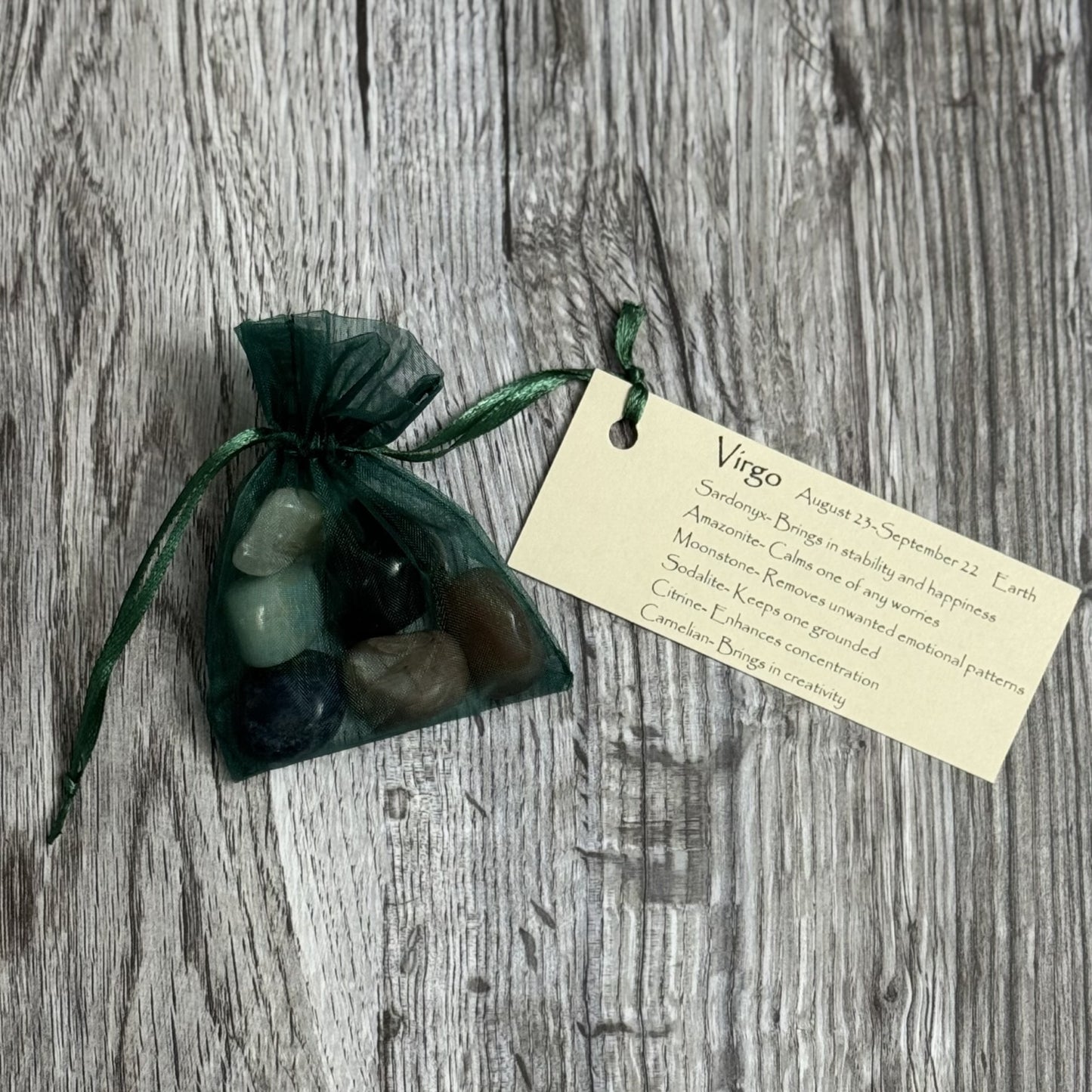 Set of stones in a green drawstring bag with a tag on a wooden surface