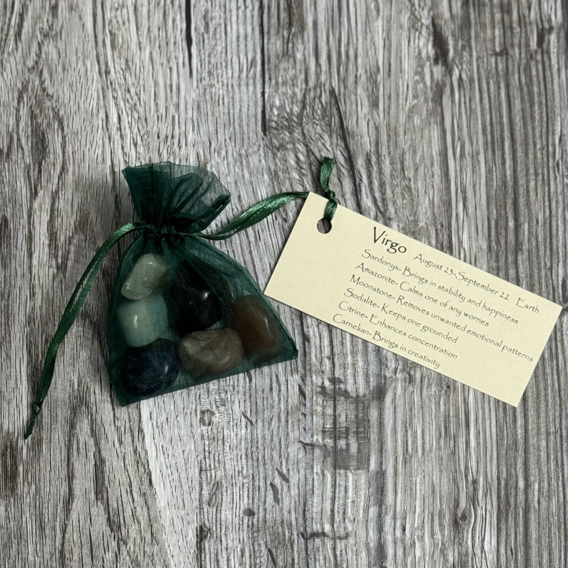 Set of stones in a green drawstring bag with a tag on a wooden surface