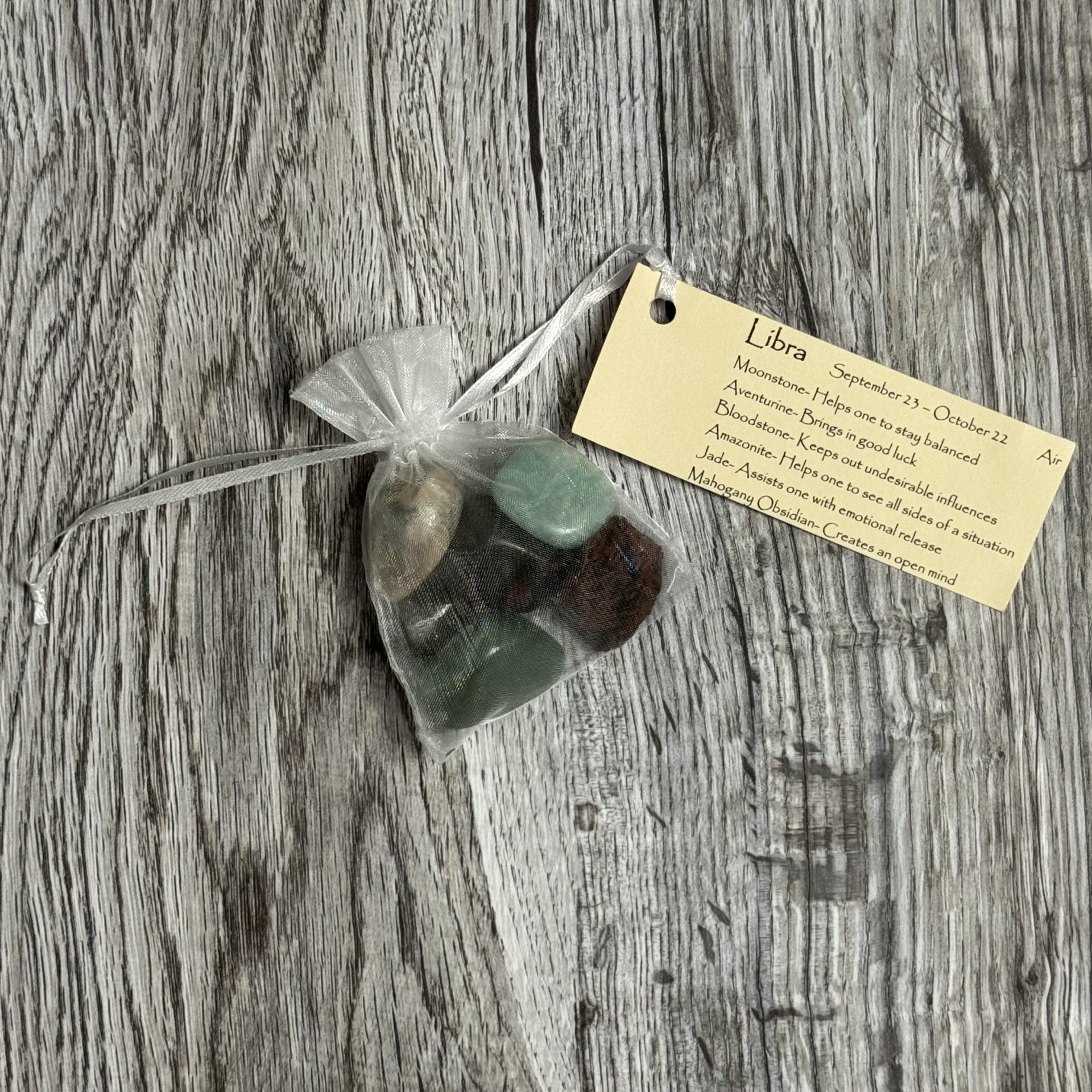 Green stones in a clear bag with a yellow tag on a wooden surface