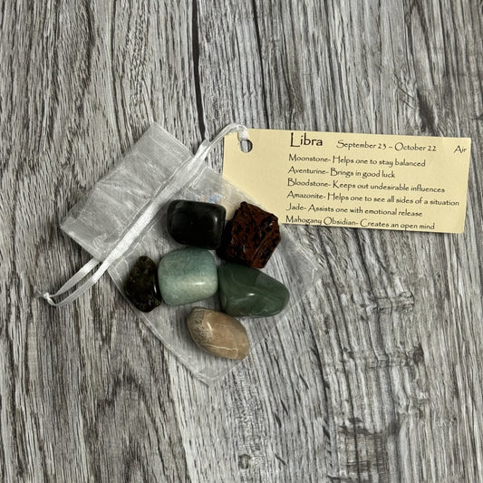 Set of stones on a wooden surface with a Libra zodiac card.