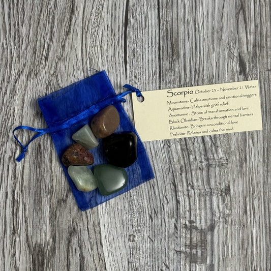 Set of stones in a blue drawstring bag with a Scorpio card on a wooden surface
