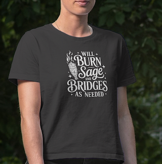 Person wearing a Dark Grey Heather 'Will burn sage and bridges' tee against a green leafy background