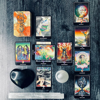 A collection of tarot cards laid out on a wooden surface, including a deck with various colorful illustrations and a white crystal-like object.