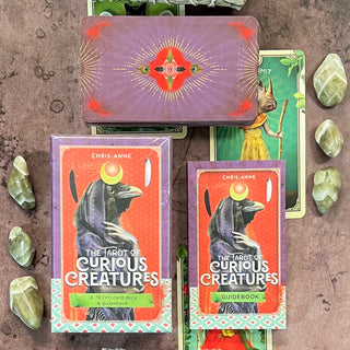 The image displays a collection of tarot cards from the deck 'The Tarot of Curious Creatures' by Chris-Anne. The cards are vividly designed with whimsical, artistic illustrations of various creatures.