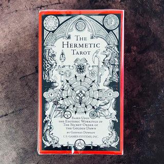 Packaging of The Hermetic Tarot by Godfrey Dowson featuring a monochromatic illustration with astrological symbols and a red border.