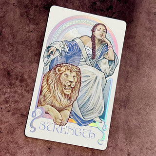 Tarot card titled 'Strength' featuring a woman with a lion on a textured brown background